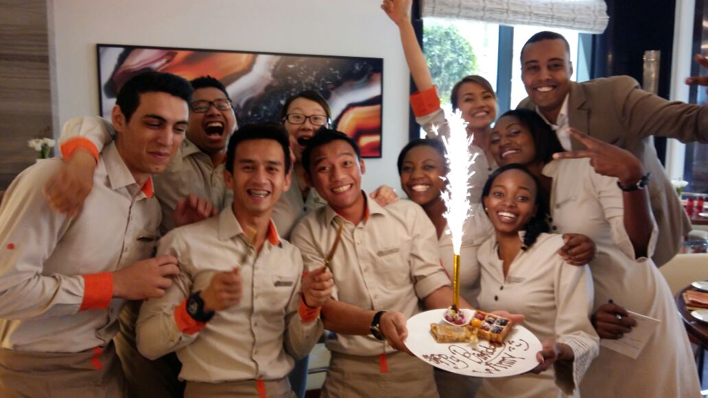 Group of hospitality staff gathered around a cake
